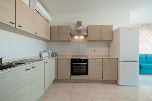una cucina con armadi in legno e frigorifero bianco di The Pinnacle Fl6 a Mellieħa