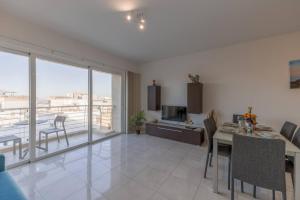 a living room with a dining table and a kitchen with a view at The Pinnacle Fl6 city escape by Homely in Mellieħa