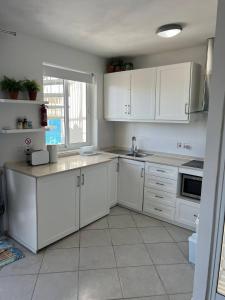 a white kitchen with white cabinets and a window at Mellieha Bay Seafront With Spectacular Views3bed in Mellieħa