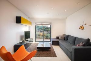 a living room with a couch and a tv at Mellieha Bay Designer Apartment By Homely in Mellieħa