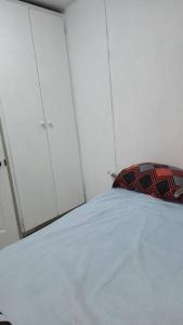 1 dormitorio con 1 cama con armarios blancos y almohada roja en Cosy Corner #2 en Bridgetown