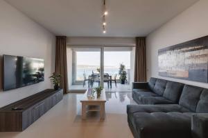 ein Wohnzimmer mit einem Sofa und einem TV in der Unterkunft Luxe 3br Melliehabay Retreat And Stunning Terrace in Mellieħa