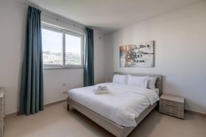 Schlafzimmer mit einem großen weißen Bett und einem Fenster in der Unterkunft Luxe 3br Melliehabay Retreat And Stunning Terrace in Mellieħa