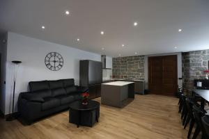 a living room with a black couch and a kitchen at Casa rural El Atardecer in Villacastín