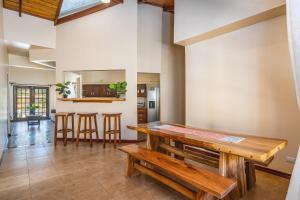 uma sala de jantar com uma mesa de madeira e bancos em Casa Amarilla em Playa Avellana