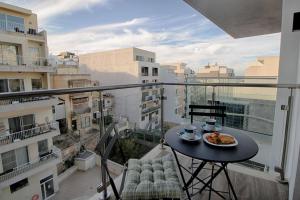 un balcón con una mesa con un plato de comida. en 3bed Mellieha With Shared Pool, en Mellieħa