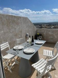 una mesa con sillas y copas de vino en el balcón en Pearlcourt 1 Bedroom Ph Mellieha, en Mellieħa