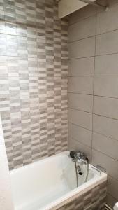 a bath tub in a bathroom with a tile wall at Résidence Les Glovettes - 2 Pièces pour 6 Personnes 614 in Villard-de-Lans