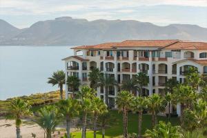 a large building with palm trees in front of a body of water at Paraiso del Mar Condominiums in Misiones de La Paz