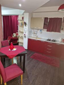 a kitchen with red cabinets and a table with red chairs at Hotel Jolie Apartments in Galaţi