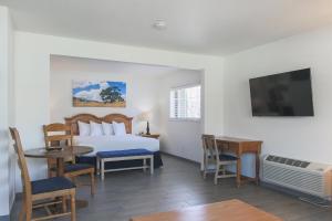 a hotel room with a bed and a table and a television at Solvang Inn & Cottages in Solvang