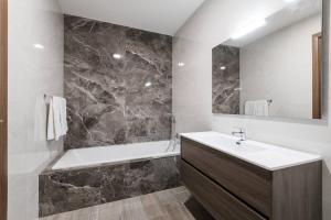 a bathroom with a sink and a bath tub at 9ten11 Seafront in Mellieħa