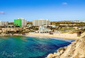 a view of a beach with hotels and buildings at 9ten11 Seafront in Mellieħa