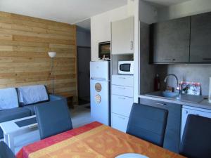 eine kleine Küche mit einem Tisch und Stühlen sowie eine Küche mit einem Kühlschrank in der Unterkunft Chalet Arrondaz - 3 Pièces pour 6 Personnes 044 in Modane