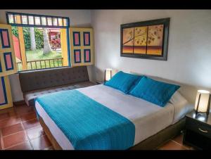 sypialnia z łóżkiem z niebieską pościelą i oknem w obiekcie BioHotel Serenity Spa w mieście Luna Park