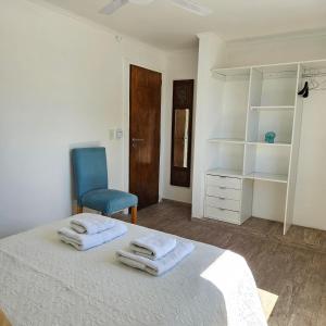 um quarto branco com uma cama e uma cadeira azul em Jacarandá, amplio departamento con terraza em Chascomús