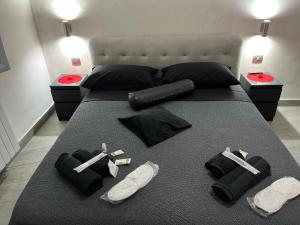 Una cama con un edredón negro con armas y zapatos. en holiday home Un posto solare, en Nápoles