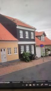 una casa negra y amarilla con techos rojos en Skrædderens hus, en Assens