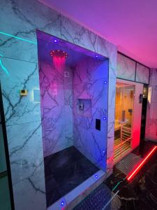 a bathroom with a marble wall and purple lights at HIGHFIELD PRIVATE SPA APARTMENT in Bradford