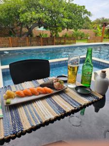 una mesa con una bandeja de comida y un vaso de cerveza en Rancharia Charme Beach - Pé na Areia en Atins