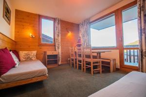 a bedroom with a bed and a desk and windows at PORTAIL G - Appartement PORTAIL 24 pour 5 Personnes 84 in Valmorel