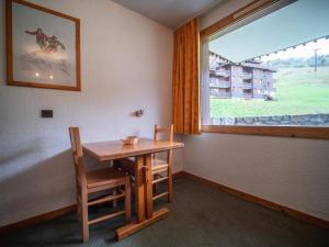 a table and chairs in a room with a window at PORTAIL G - Appartement PORTAIL 51 pour 2 Personnes 00 in Valmorel