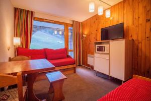 a living room with a red couch and a table at PORTAIL G - Appartement PORTAIL 40 pour 2 Personnes 17 in Valmorel