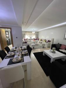 Luxueux appart à côté aéroport في Nouaceur: غرفة معيشة مع طاولة وكراسي بيضاء