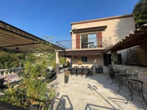 a patio with tables and chairs and a building at Rez de villa avec piscine in Menton