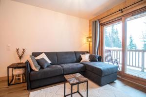 a living room with a couch and a large window at Résidence LUMI BATIMENT B - Appartement LUMI B 814 in Valmorel