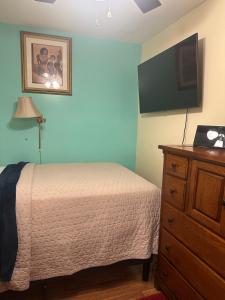 a bedroom with a bed and a dresser with a flat screen tv at Genevieve’s comfort pad in Jersey City