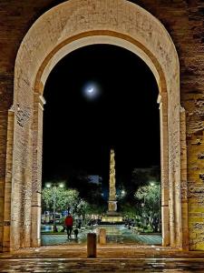 une arche en pierre avec une statue dans un parc la nuit dans l'établissement Li tufi Salento casa vacanze Puglia, à Monteroni di Lecce