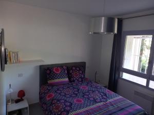 - une chambre avec un lit doté d'une couette violette et d'une fenêtre dans l'établissement Bandol, T3, les pieds dans l'eau, presqu'île du Capelan, à Bandol