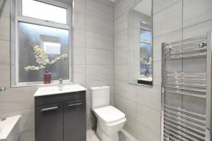 baño con aseo y lavabo y ventana en Leicester Serviced Accomodation with Free Sky and BT Sports, en Leicester