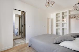 a white bedroom with a bed and a mirror at Appartement Nation in Paris