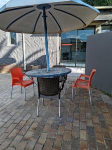a table and chairs with an umbrella on a patio at Sem's Guest Cottage in Edenvale