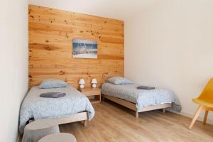 sypialnia z 2 łóżkami i drewnianą ścianą w obiekcie La maison du pêcheur w mieście La Cotinière