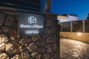 a sign for a hotel on a stone wall at Mateo & Filipos Luxury Villas in Ambelókipoi