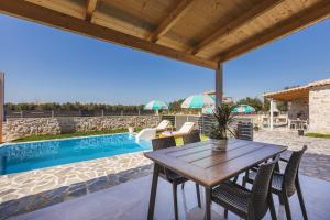 a patio with a table and chairs and a swimming pool at Mateo & Filipos Luxury Villas in Ambelókipoi