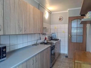 a kitchen with wooden cabinets and a stove top oven at Legnicka Budget Stay - Grysko Apartament's in Szczecin