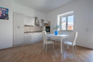 a kitchen and dining room with a white table and chairs at Settessenze Residence & Rooms in Agropoli
