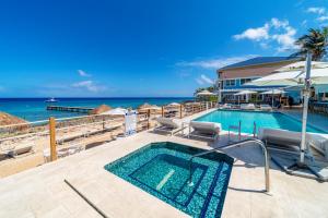 a swimming pool with chairs and the ocean in the background at Cobalt Coast Resort in West Bay