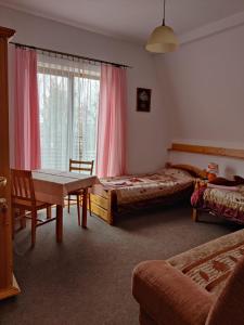 a bedroom with two beds and a table and a window at Wojterówka in Dziwnów