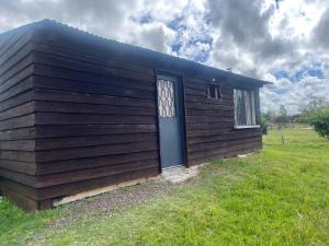 a small cabin with a blue door in a field at 0 es 3 Dos in Treinta y Tres