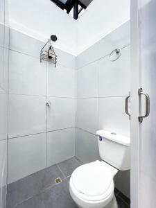 a white bathroom with a toilet and a shower at Baku Laureles Hostel in Medellín