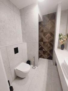 a white bathroom with a toilet and a sink at Przestronny apartament, ogródek, miejsca postojowe w garażu in Krakow