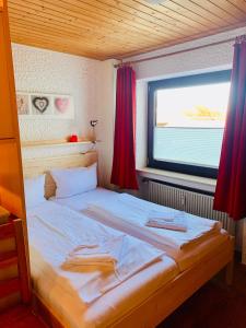 a bed in a room with a window with red curtains at Allgäu Appartementhaus Appartement ALLGÄU 08 in Pfronten