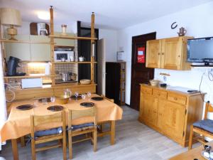 a kitchen with a wooden table with chairs and a kitchen with a refrigerator at Résidence Bel'aval - 3 Pièces pour 6 Personnes 364 in Les Contamines-Montjoie