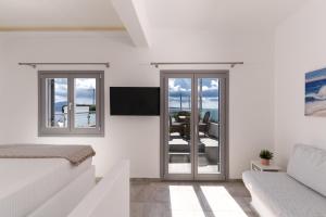 uma sala de estar branca com uma porta de vidro deslizante em Enalion White Suites Oia em Oia
