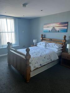 a bedroom with a bed with a blue wall at Promenade Sea View Apartment in Ballycastle